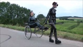 Latex Pony Outdoor. Female latex pony slave outdoor dominated by her Mistress using her whip to guide her in pulling a cart so that her owner can have fun being carried in this way