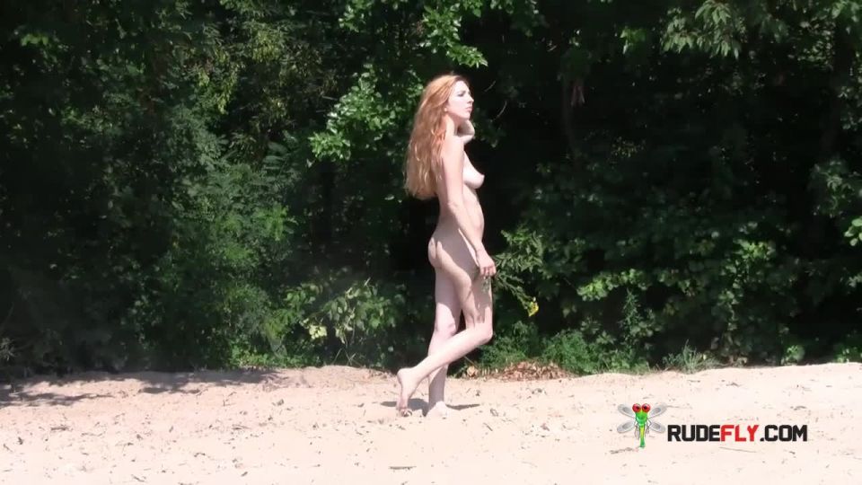 Wet nudist kicks up some water at a nude  beach